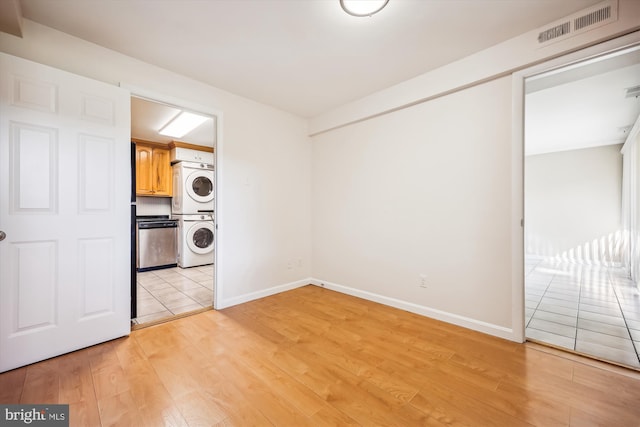 clothes washing area with stacked washer / dryer and light hardwood / wood-style flooring