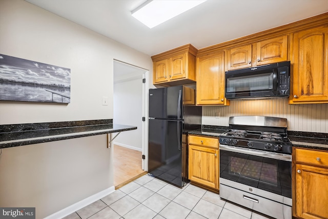 kitchen with light tile patterned floors, dark stone counters, and black appliances