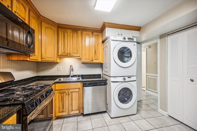 washroom with sink, light tile patterned floors, and stacked washer and clothes dryer