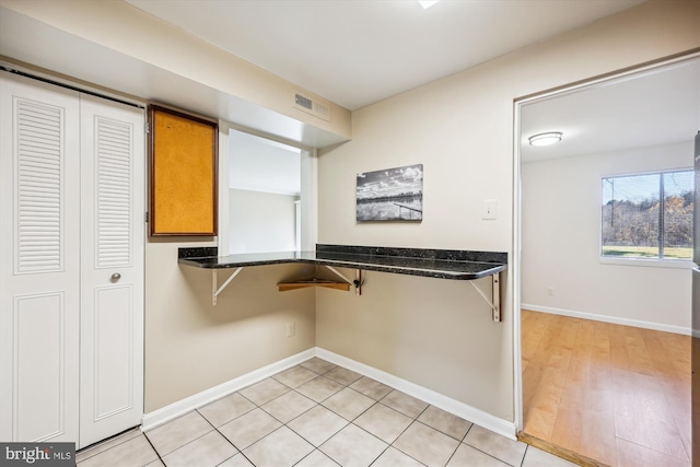 kitchen with light tile patterned flooring and dark stone countertops