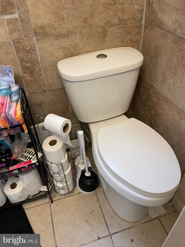 bathroom with toilet and tile walls