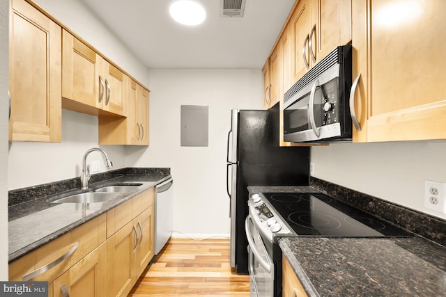 kitchen featuring sink, light hardwood / wood-style flooring, dark stone countertops, light brown cabinetry, and appliances with stainless steel finishes