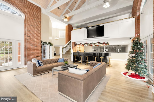 living room with beamed ceiling, high vaulted ceiling, wood ceiling, ceiling fan with notable chandelier, and light wood-type flooring