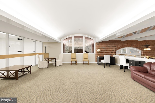 carpeted living room featuring ceiling fan and brick wall