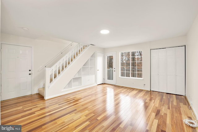 unfurnished living room featuring hardwood / wood-style floors and built in shelves