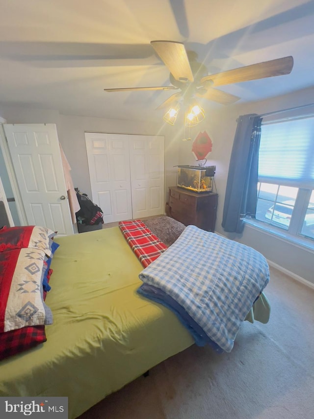 carpeted bedroom with ceiling fan and a closet