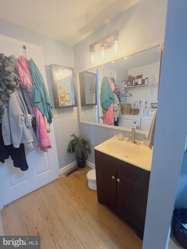 bathroom featuring wood-type flooring, vanity, and washing machine and clothes dryer