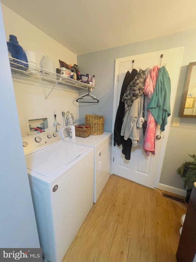 clothes washing area with light wood-type flooring and washing machine and dryer