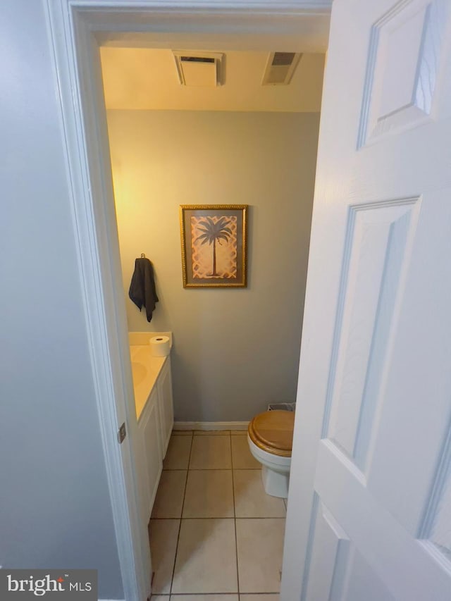 bathroom with toilet, vanity, and tile patterned flooring