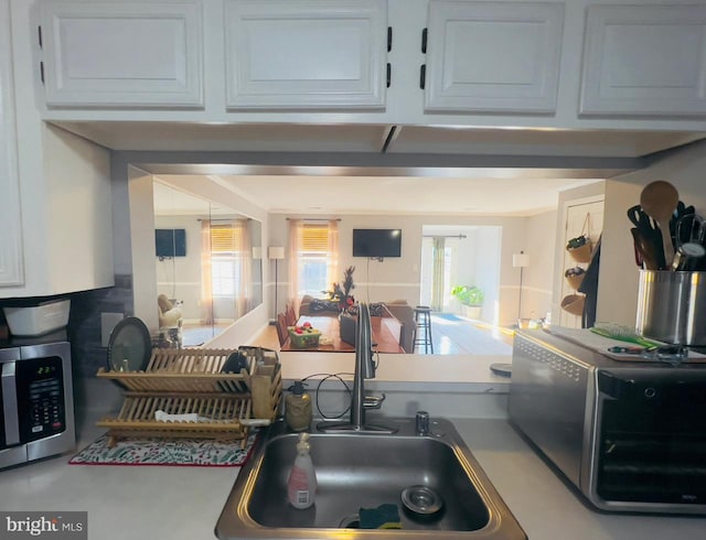 kitchen featuring concrete flooring, white cabinetry, and sink