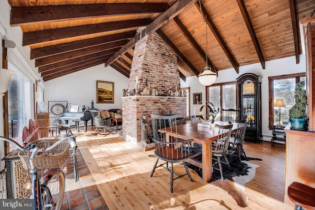 dining room featuring a fireplace, wood-type flooring, beamed ceiling, and high vaulted ceiling