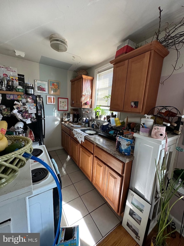 kitchen with white stove, light tile patterned floors, and sink