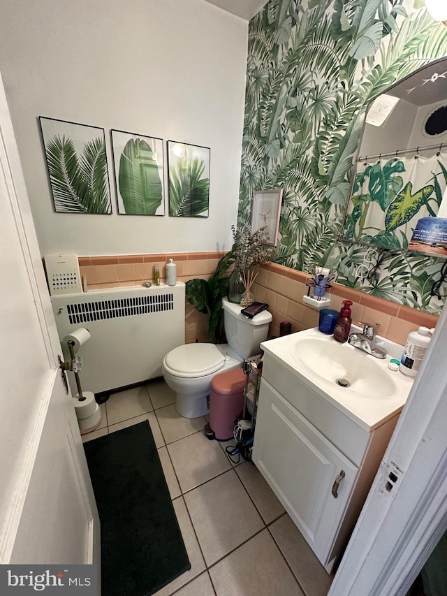 bathroom featuring vanity, radiator, tile patterned flooring, toilet, and tile walls