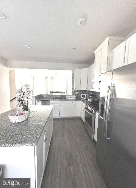 kitchen featuring white cabinetry, dark stone countertops, stainless steel appliances, and dark hardwood / wood-style flooring