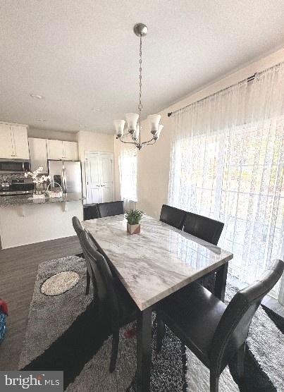 dining space featuring hardwood / wood-style flooring, a textured ceiling, and an inviting chandelier