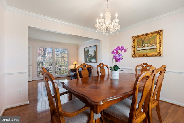 dining space with dark hardwood / wood-style flooring, an inviting chandelier, and ornamental molding