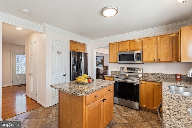 kitchen with stainless steel appliances, sink, a center island, and light stone countertops