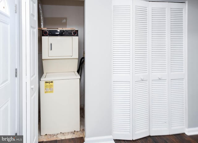 laundry area featuring stacked washer / drying machine and dark hardwood / wood-style floors