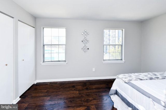 bedroom featuring two closets and dark hardwood / wood-style flooring