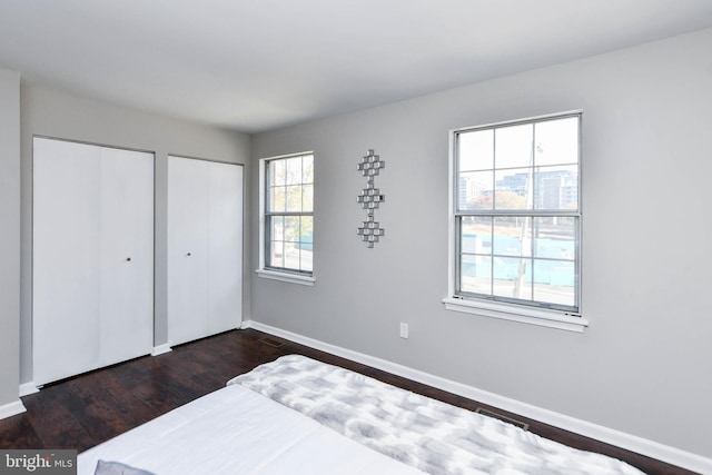 bedroom with multiple closets and dark hardwood / wood-style flooring