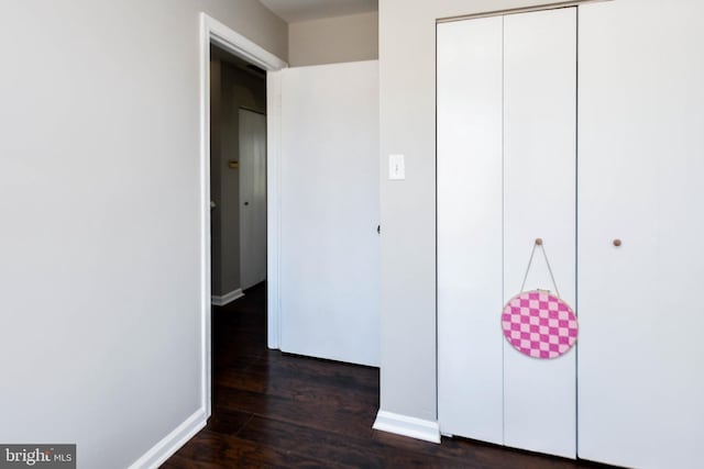 unfurnished bedroom with dark wood-type flooring and a closet