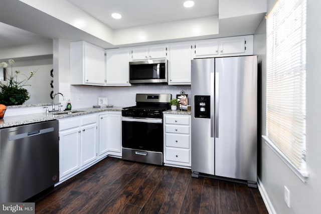 kitchen with sink, light stone countertops, white cabinets, appliances with stainless steel finishes, and dark hardwood / wood-style flooring