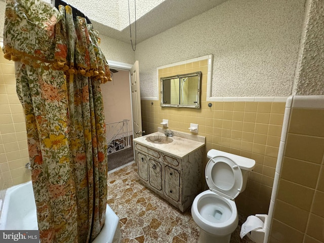 bathroom with vanity, tile walls, a textured ceiling, and toilet