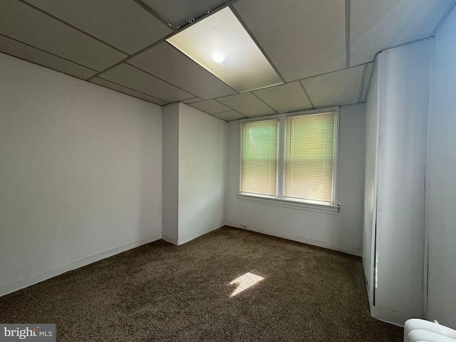 unfurnished room with a paneled ceiling and carpet flooring