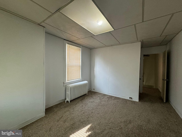 carpeted empty room with a drop ceiling and radiator heating unit