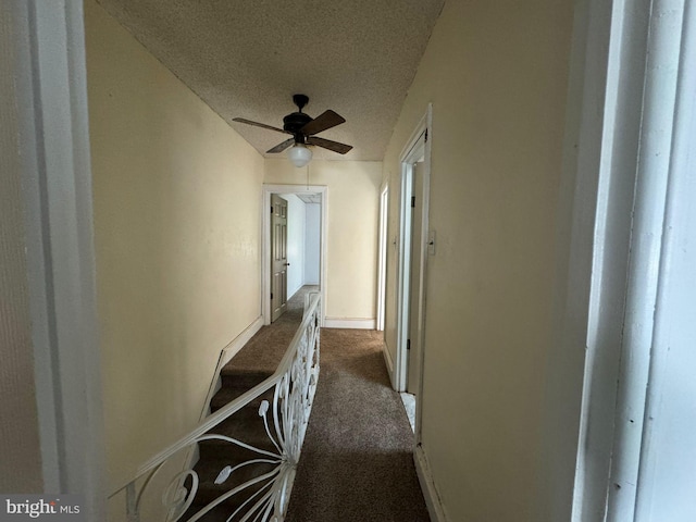 hall with a textured ceiling and carpet flooring