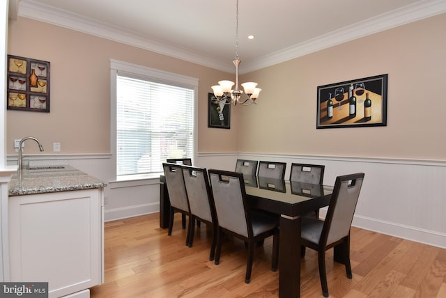 dining space with a notable chandelier, sink, light hardwood / wood-style flooring, and ornamental molding