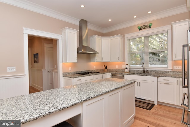 kitchen featuring white cabinetry, appliances with stainless steel finishes, sink, and wall chimney range hood