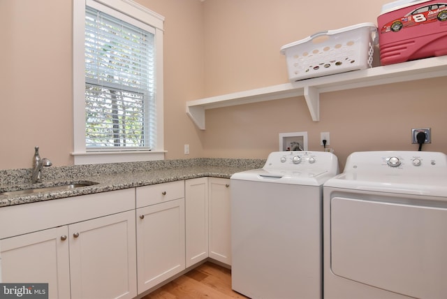 laundry area with light wood-type flooring, a wealth of natural light, sink, and washer and dryer