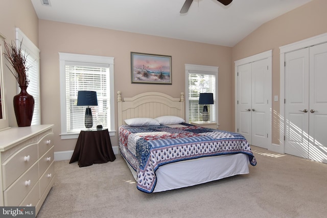 carpeted bedroom featuring vaulted ceiling, two closets, and ceiling fan