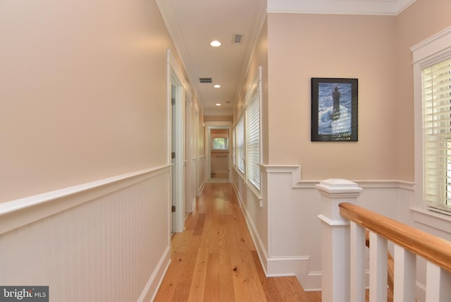 hall with ornamental molding and light wood-type flooring