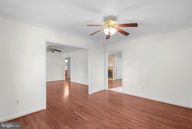 empty room featuring hardwood / wood-style floors, a textured ceiling, ceiling fan, and ornamental molding