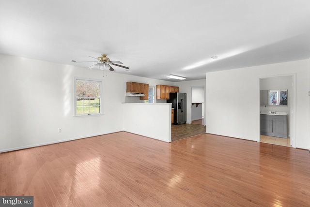 unfurnished living room featuring ceiling fan, sink, and light hardwood / wood-style flooring