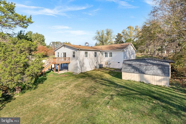 rear view of property featuring central air condition unit, a deck, a storage shed, and a lawn