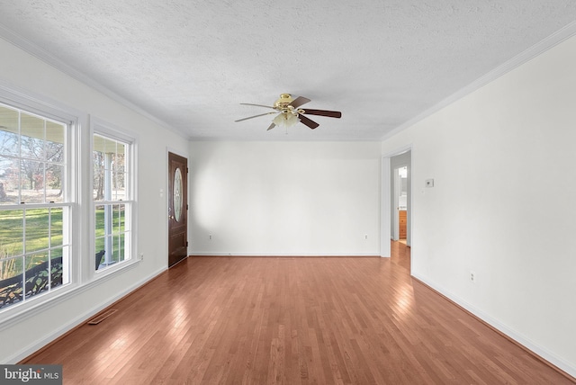 empty room featuring a textured ceiling, hardwood / wood-style flooring, plenty of natural light, and ceiling fan