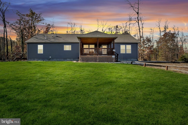 view of front of property featuring roof with shingles, a deck, and a front yard