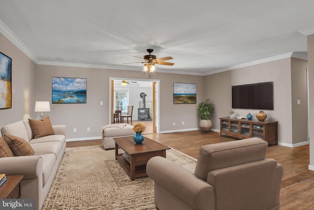 living room with baseboards, wood finished floors, a wood stove, and crown molding