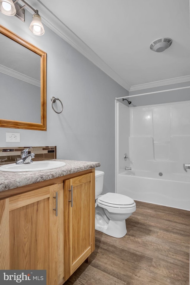 full bathroom with wood-type flooring, toilet, ornamental molding, vanity, and bathing tub / shower combination