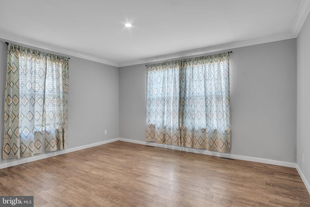 empty room featuring crown molding, baseboards, and wood finished floors