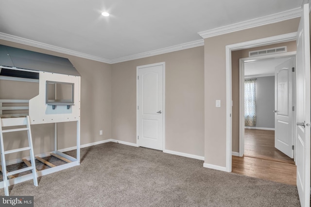 unfurnished bedroom with crown molding, carpet, visible vents, and baseboards