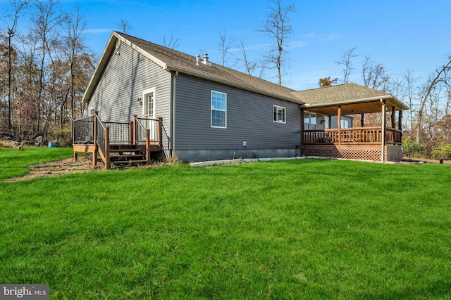 rear view of house with a wooden deck, a lawn, and roof with shingles