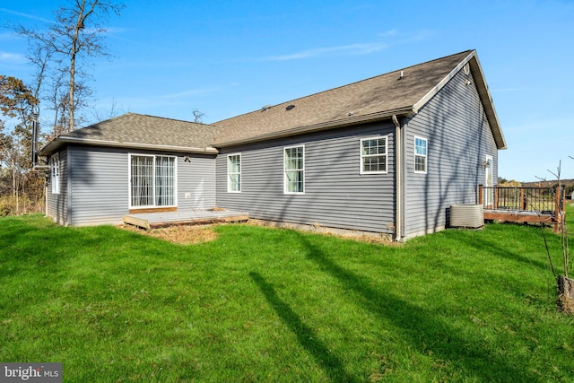 back of property featuring a wooden deck, a lawn, and roof with shingles