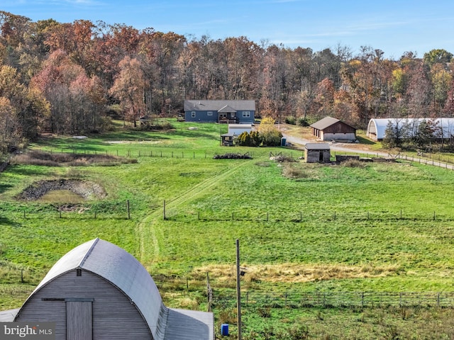 view of yard with an outbuilding, fence, a rural view, and a forest view