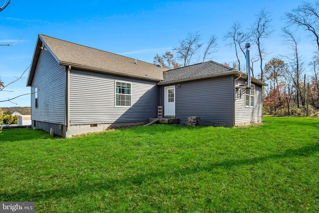 back of house featuring a shingled roof, a lawn, and crawl space