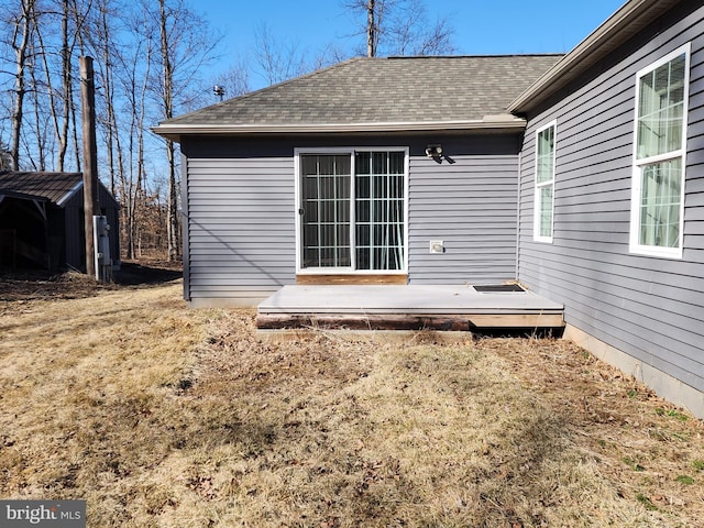 rear view of property featuring roof with shingles and a wooden deck