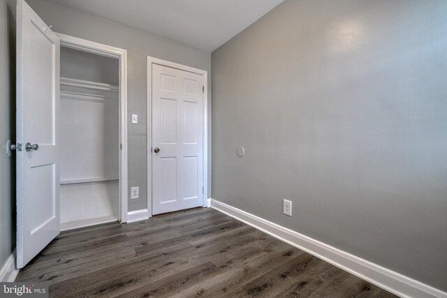 unfurnished bedroom featuring dark hardwood / wood-style floors and a closet